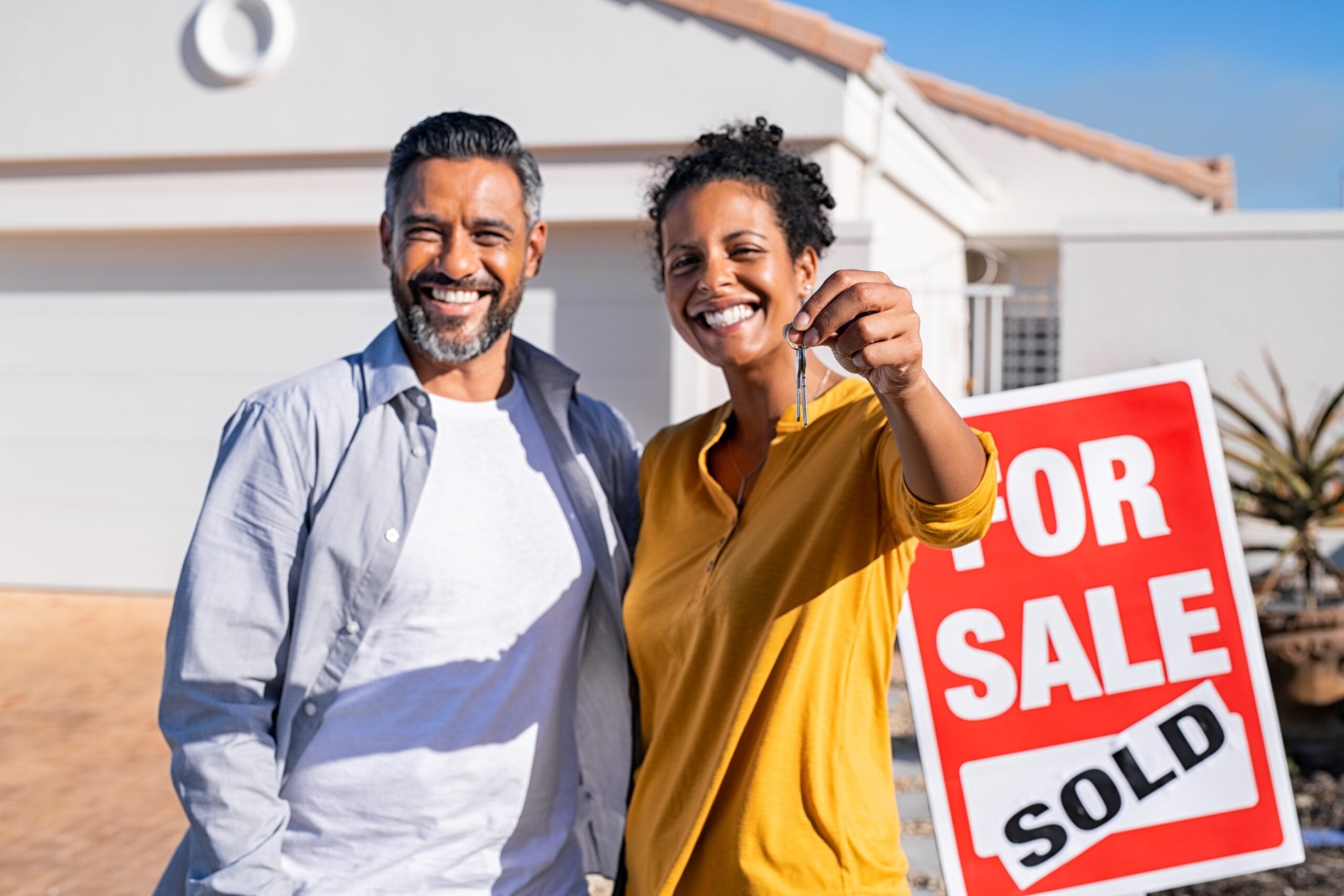 Portrait of happy mixed race couple holding house keys standing