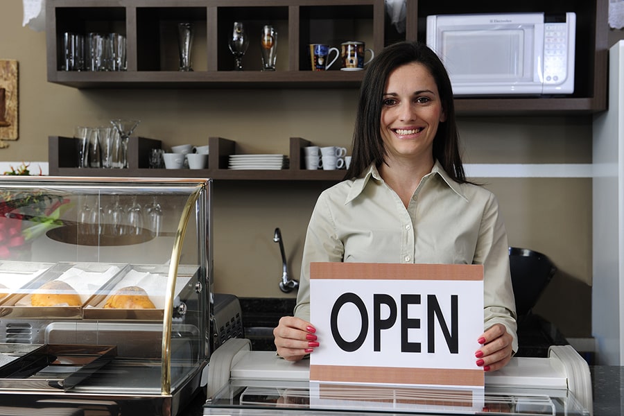 woman small business owner holding an Open sign