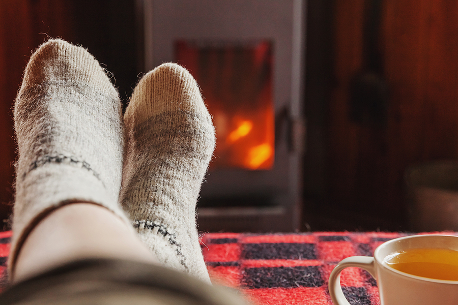 Feet Legs In Winter Clothes Wool Socks And Cup Tea At Fireplace
