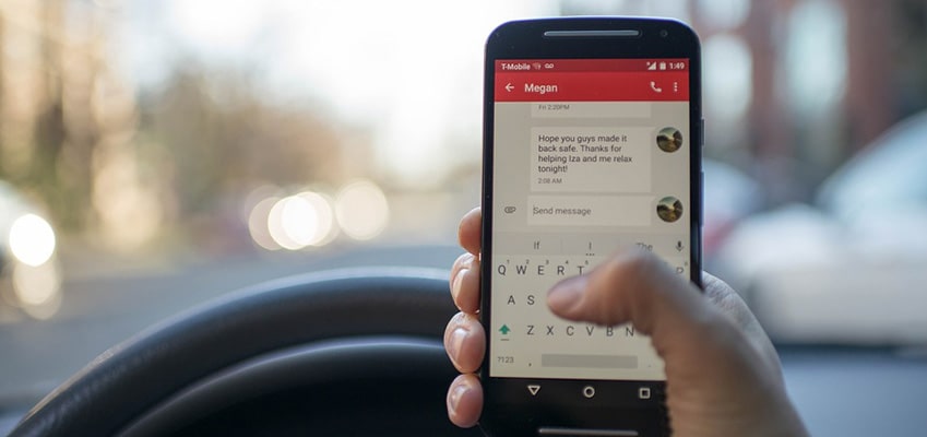 driver with smartphone over steering wheel while driving