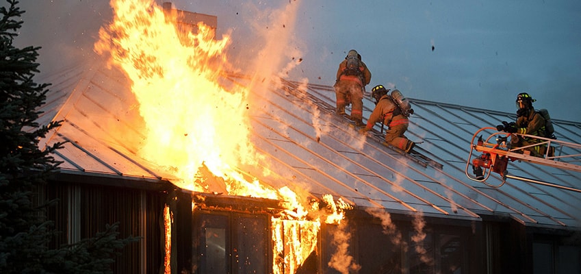 House fire with firefighters breaking through the roof